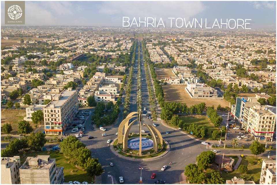 Aerial view of Bahria Town Lahore featuring a large roundabout monument and tree-lined boulevard.