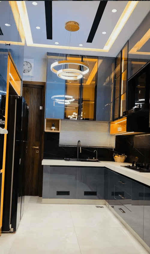 Sleek modern kitchen featuring grey cabinetry, integrated lighting, and a stylish double-ring pendant light.