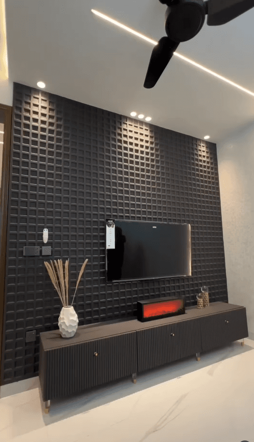 Dark waffle-patterned accent wall featuring a mounted television above a sleek fluted media console.