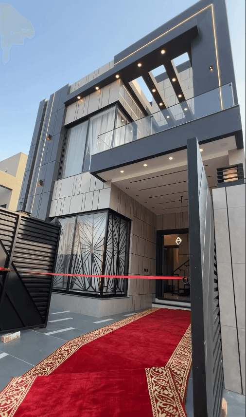 Modern grey house with a red carpet and ceremonial ribbon across the front entrance.